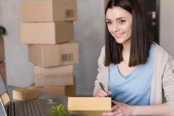 woman writing something next to laptop